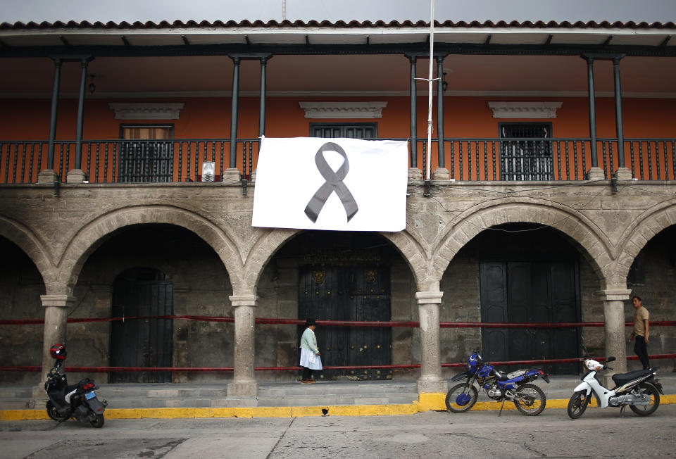A woman passes below a big black ribbon displayed as a symbol of people who were killed during protests against new President Dina Boluarte, in Ayacucho, Peru, Sunday, Dec. 18, 2022. The eight deaths this week that converted Ayacucho into the epicenter of violence in Peru's still unfolding crisis is for many a stark reminder of the region's bloody past and longstanding neglect by authorities in the far-away capital. (AP Photo/Hugo Curotto)