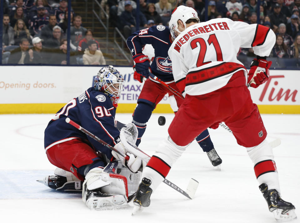 Columbus Blue Jackets' Elvis Merzlikins, left, of Latvia, makes a save against Carolina Hurricanes' Nino Niederreiter, of Switzerland, during the first period of an NHL hockey game Thursday, Jan. 16, 2020, in Columbus, Ohio. (AP Photo/Jay LaPrete)