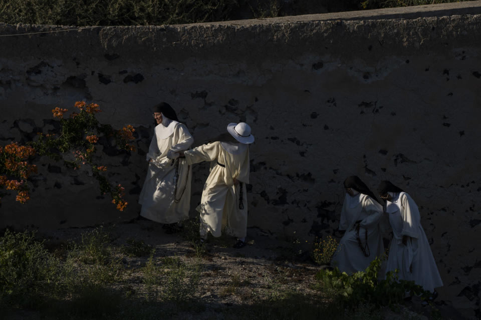 From left to right, cloistered nuns Sister María Flor, Sister María de la Trinidad, Sister María de Jesús and Sister María Teresa walk in the garden of the Catholic Monastery of St. Catherine on the Greek island of Santorini on Wednesday, June 15, 2022. When not praying in church or practicing sacred music and hymns, the nuns tend to a garden where they grow fruits and vegetables. (AP Photo/Petros Giannakouris)