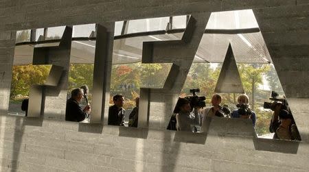 Journalists are reflected in a logo at the FIFA headquarters after a meeting of the executive committee in Zurich October 4, 2013. REUTERS/Arnd Wiegmann/Files