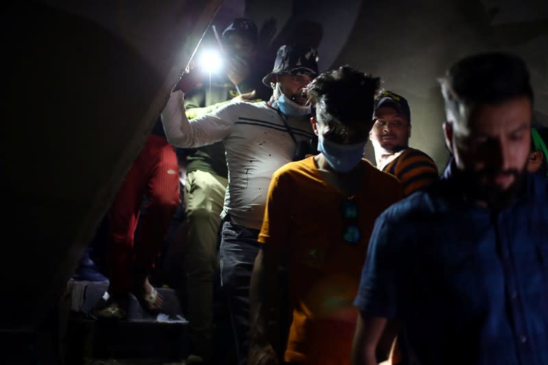 Iraqi demonstrators use the light while they walk inside the high-rise building, called by Iraqi the Turkish Restaurant Building, during anti-government protests in Baghdad