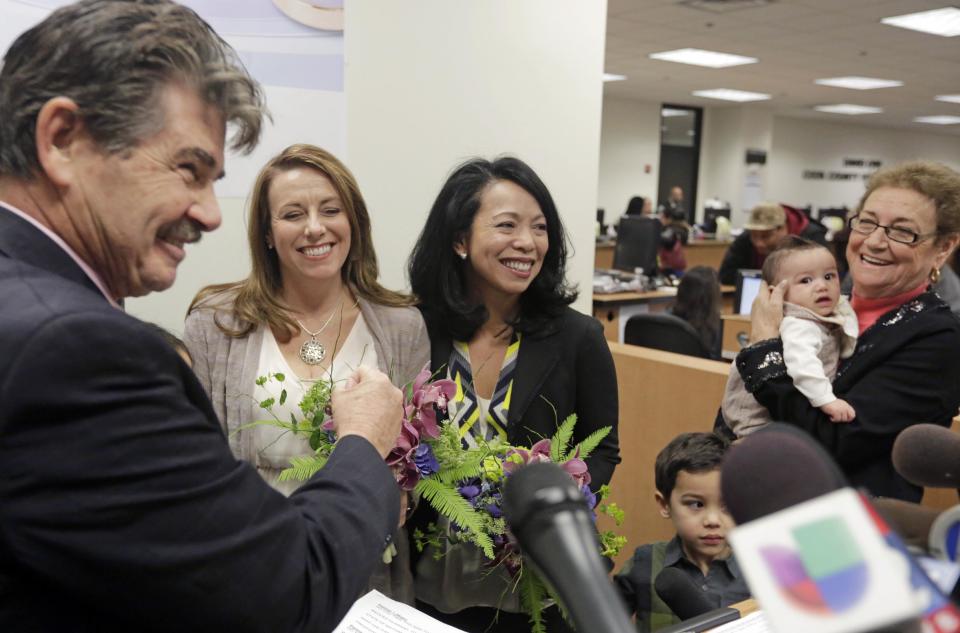 Cook County Clerk David Orr, left, performs a marriage ceremony for Theresa Volpe, second from left, and Mercedes Santos on Friday, Feb. 21, 2014, in Chicago. Same-sex couples in Illinois' Cook County began receiving marriage licenses immediately after a federal judge's ruling Friday that some attorneys could give county clerks statewide justification to also issue the documents right away. (AP Photo/M. Spencer Green)