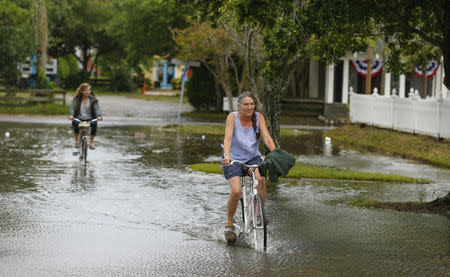 People ride their bicycles through a flooded street after Hurricane Arthur passed through in Manteo, North Carolina July 4, 2014. REUTERS/Chris Keane