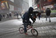 A man rides a bicycle through falling snow through Times Square in New York January 26, 2015. REUTERS/Mike Segar