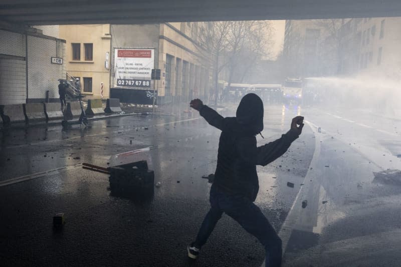 A protester throws stones towards the police during clashes following a protest called by the farmers' organizations Federation Unie de Groupements d'Eleveurs et d'Agriculteurs (FUGEA), Boerenforum and MAP, as the EU agriculture ministers are meeting to discuss rapid and structural responses to the crisis facing the agricultural sector. Nicolas Maeterlinck/Belga/dpa