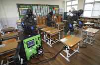 South Korean army soldiers spray disinfectant to help reduce the spread of the new coronavirus in a class at Cheondong elementary school in Daejeon, South Korea, Thursday, July 2, 2020. South Korea reported dozens of new cases as the virus continues to spread beyond the capital area and reach cities like Gwangju, which has shut schools and tightened social restrictions after dozens were found infected this week. (Kim Jun-beom/Yonhap via AP)