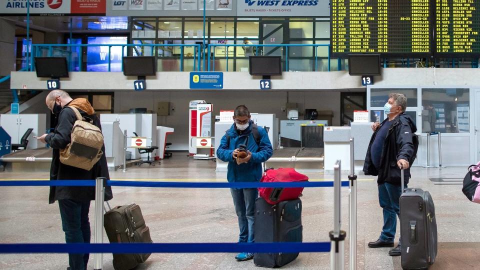 Passagiere mit Smartphones in einer Schlange im Internationalen Flughafen von Vilnius.