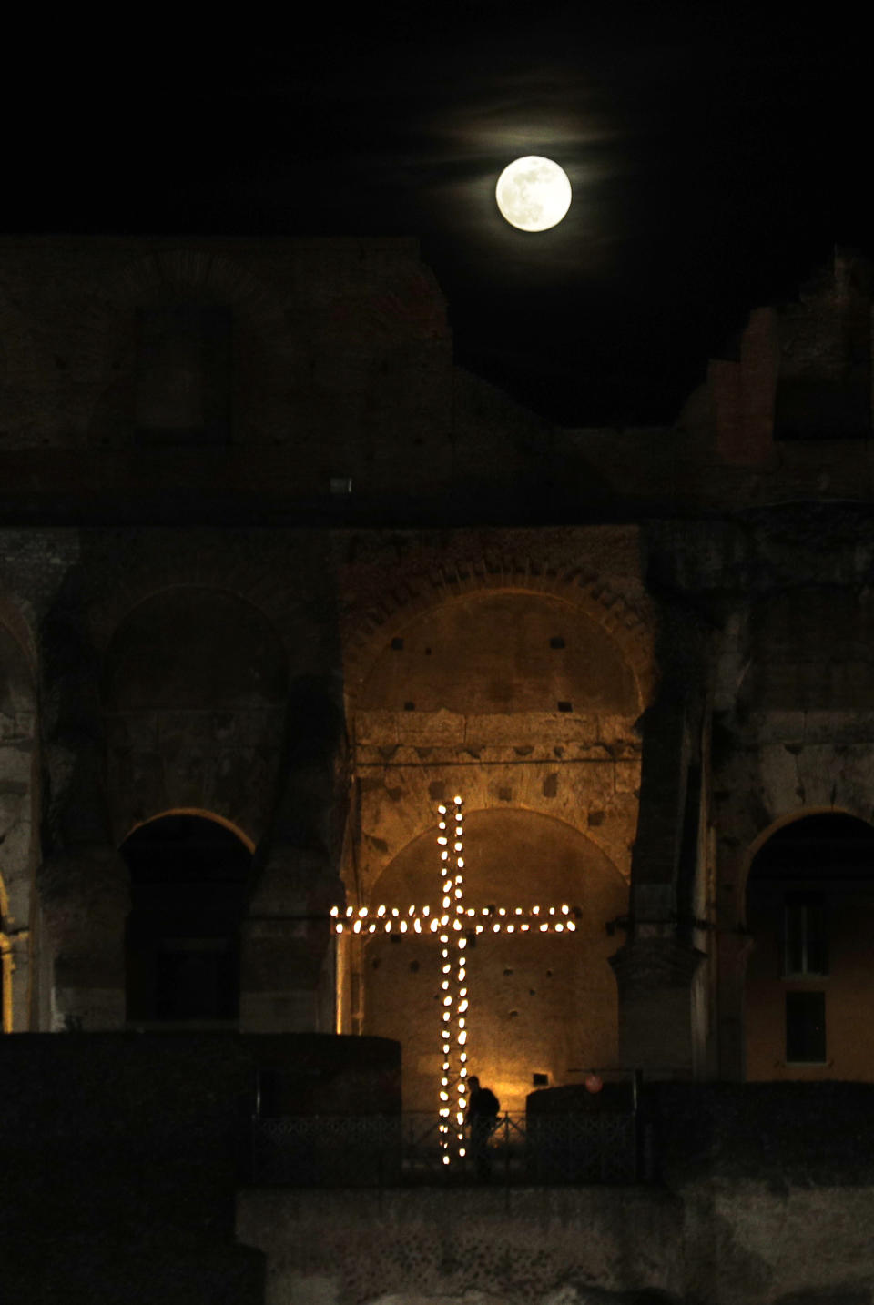 The moon rises over the Colosseum during the Via Crucis (Way of the Cross) torchlight procession in front of Rome's Colosseum on Good Friday, a Christian holiday commemorating the crucifixion of Jesus Christ and his death at Calvary, in Rome, Friday, April 19, 2019. (AP Photo/Gregorio Borgia)