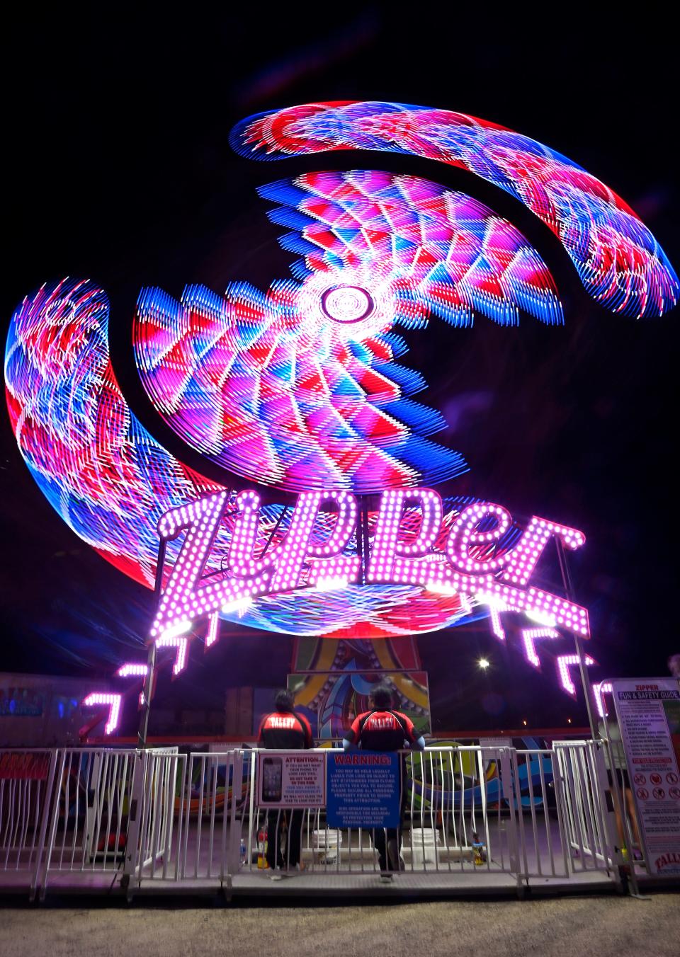 Ride operators watch as the Zipper ride spins around, its lights blurred in this long exposure, at the San Angelo Rodeo carnival Friday. The carnival will be open through the month.