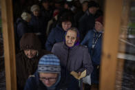 Ukrainian men and women queue inside a church to receive humanitarian aid donated by European Union in Bucha, in the outskirts of Kyiv, on Tuesday, April 19, 2022. Citizens of Bucha are still without electricity, water and gas after more than 44 days since the Russian invasion began. (AP Photo/Emilio Morenatti)