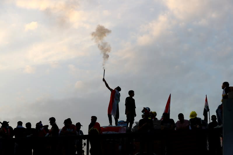 An Iraqi demonstrator fires a flare towards riot police during the ongoing anti-government protests in Baghdad