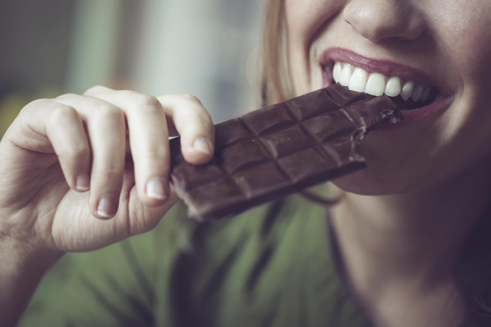 close up shot of a woman biting into a block of chocolate