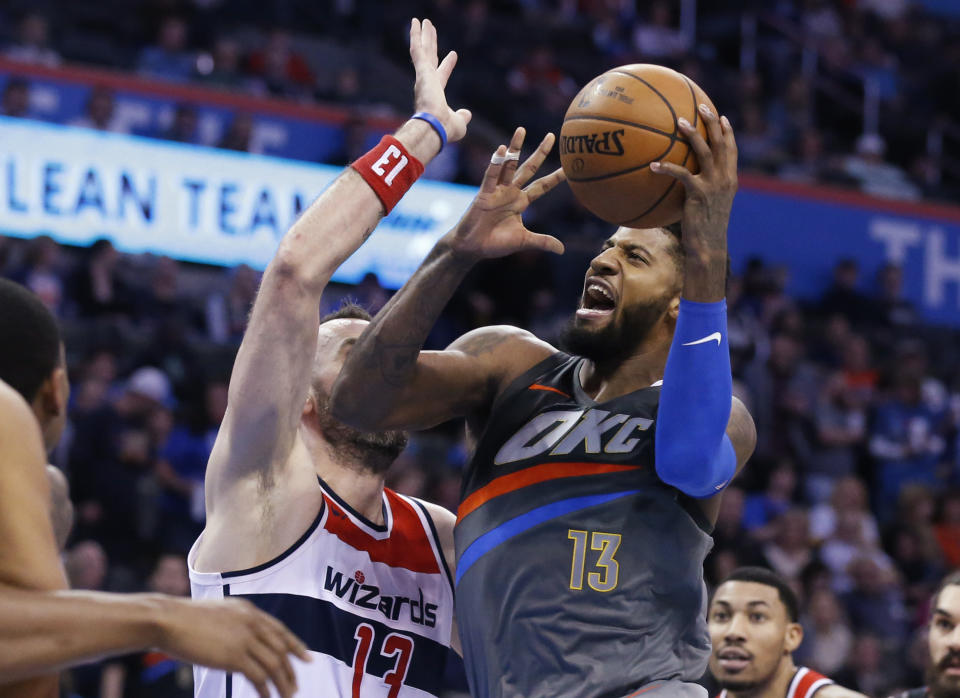 Oklahoma City Thunder forward Paul George (13) drives to the basket past Washington Wizards center Marcin Gortat (13) during the third quarter of an NBA basketball game in Oklahoma City, Thursday, Jan. 25, 2018. (AP Photo/Sue Ogrocki)