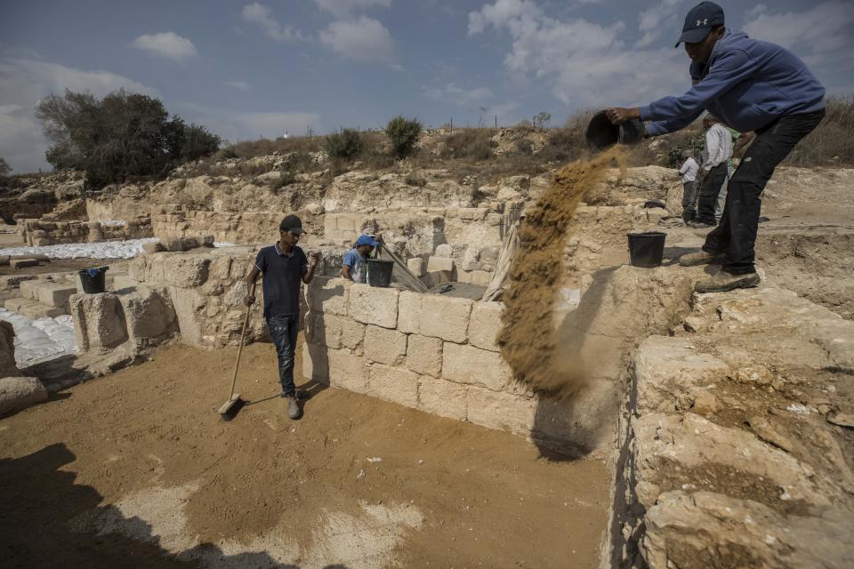 Workers of the Israel Antiquities Authority cover sand an ancient church that was recently uncovered in Beit Shemesh, near Jerusalem. Wednesday, Oct. 23, 2019. Israeli archaeologists have revealed an elaborately decorated Byzantine church dedicated to an anonymous martyr that was recently uncovered near Jerusalem. The Israel Antiquities Authority showcased some of the finds from the nearly 1,500-year-old structure on Wednesday after three years of excavations. (AP Photo/Tsafrir Abayov)