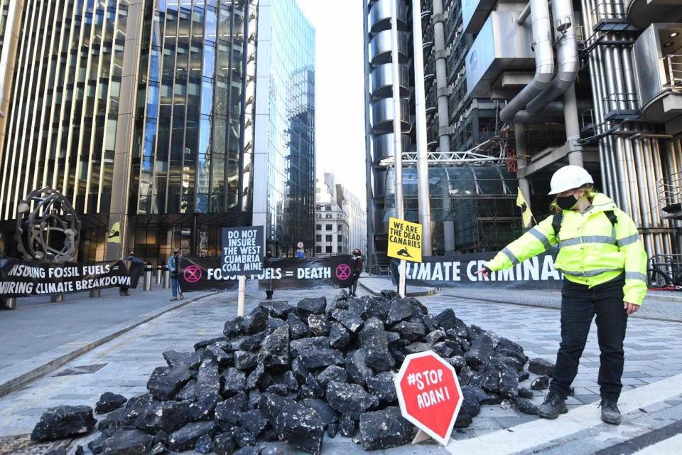 <p>An activist points to a mound of fake coal outside insurance market in central London</p> (Gareth Morris)