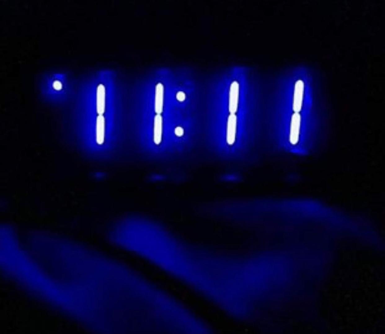 digital alarm clock in the dark with time in blue numbers reading 11 11