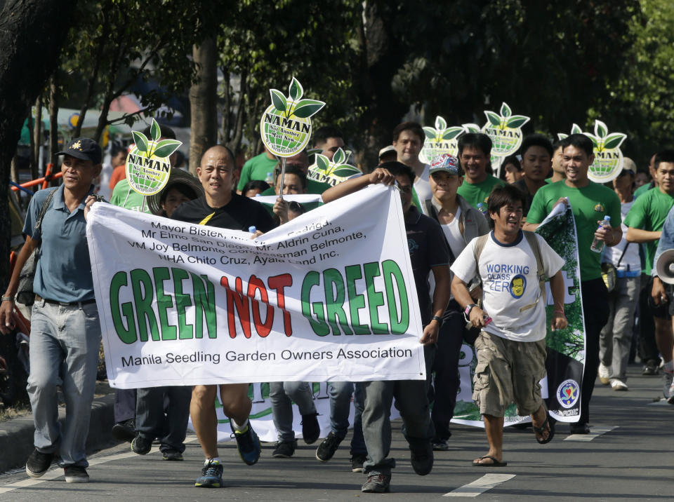 In this Feb. 20, 2014 photo, Roman Catholic priest Father Robert Reyes jogs with supporters during a protest against the demolition of an informal settlers community that will pave the way for the construction of shopping malls in Quezon city northeast of Manila, Philippines. For more than 30 years, Reyes, dubbed the “running priest” by the local media, has been a constant critic of corruption in the Philippines and often times the church itself, which he charges has abandoned its obligation to help the poor and sided with those in power in Asia’s largest Roman Catholic nation. (AP Photo/Bullit Marquez)