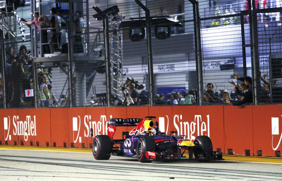 Red Bull Formula One driver Sebastian Vettel of Germany takes the chequered flag to win the Singapore F1 Grand Prix as team members cheer at the Marina Bay street circuit in Singapore September 22, 2013. Vettel cruised to a third straight Singapore Grand Prix victory on Sunday and moved closer to a fourth consecutive Formula One world title with a dominant drive under the floodlights at the Marina Bay Street Circuit. REUTERS/Edgar Su (SINGAPORE - Tags: SPORT MOTORSPORT F1)