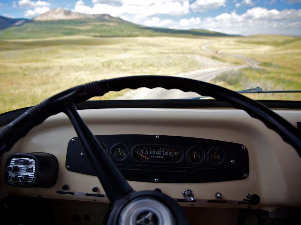 Vintage motor home dashboard looking out onto the dirt road ahead.