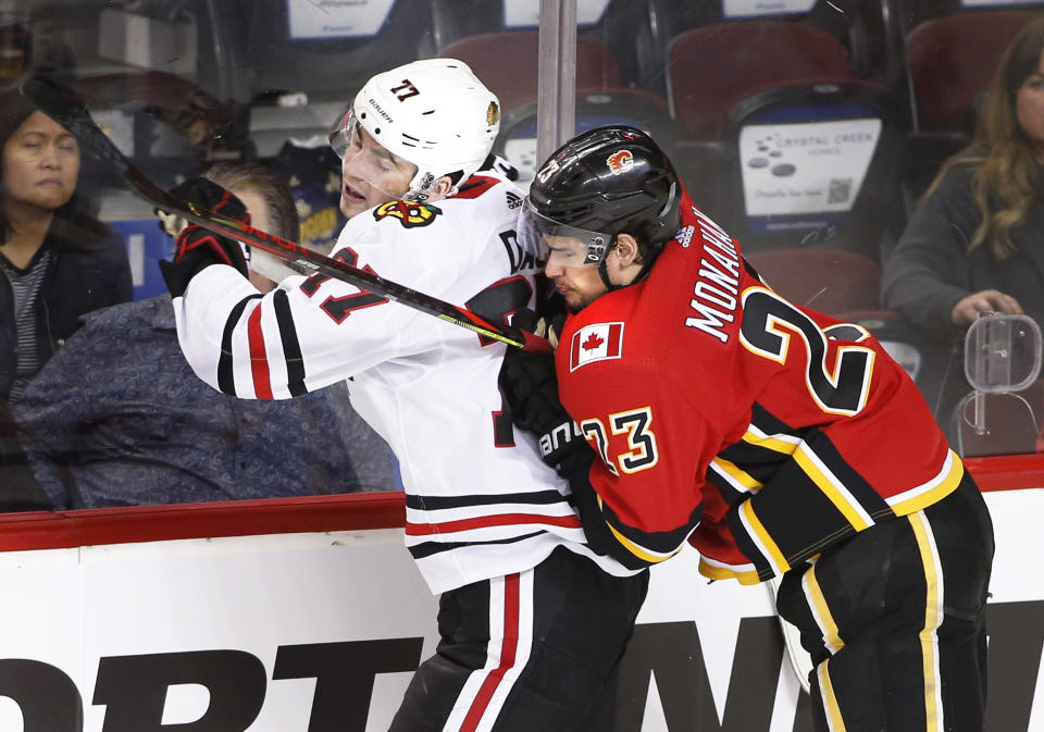 Calgary Flames center Sean Monahan (23) checks Chicago Blackhawks center Kirby Dach (77) during the third period of an NHL hockey game Saturday, Feb. 15, 2020, in Calgary, Alberta. (Larry MacDougal/The Canadian Press via AP)