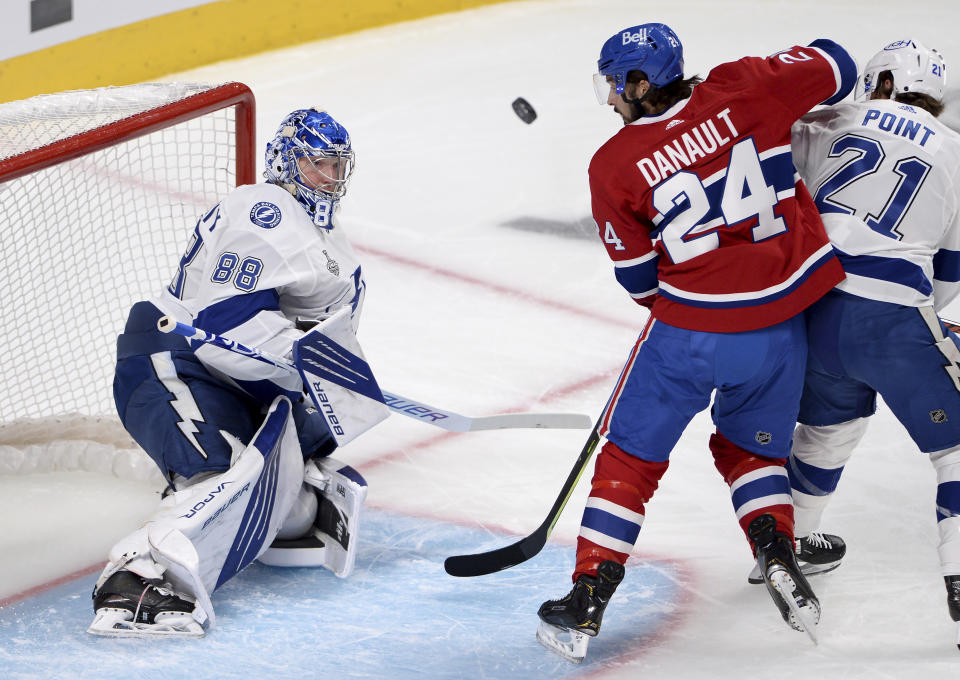 Tampa Bay Lightning's goaltender Andrei Vasilevskiy (88) makes a save as teammate Brayden Point (21) and Montreal Canadiens' Phillip Danault (24) tussle outside the crease during the first period of Game 4 of the NHL hockey Stanley Cup final in Montreal, Monday, July 5, 2021. (Ryan Remiorz/The Canadian Press via AP)