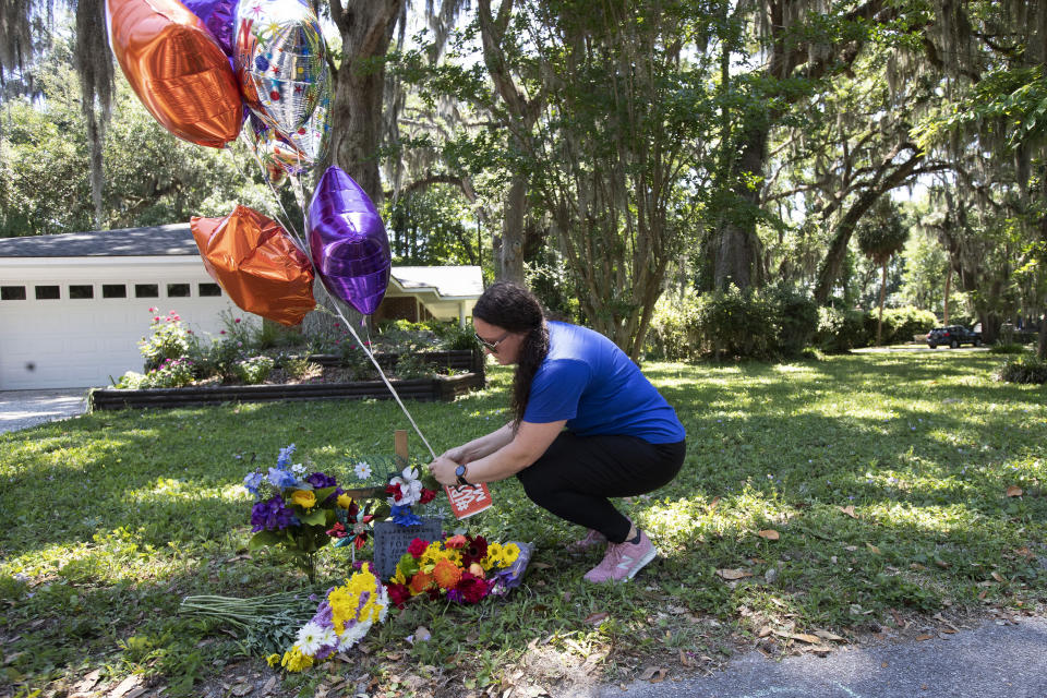 REMOVES “UNARMED” AND ADDS THAT AUTHORITIES HAVE NOT CONFIRMED THAT ARBERY WAS EITHER ARMED OR UNARMED - Erica Smith, of Brunswick, Ga., leaves a small paper sign on a memorial at the spot where Ahmaud Arbery was shot and killed Friday, May 8, 2020, in Brunswick Ga. Two men have been charged with murder in the February shooting death of Arbery, a black man in his mid-20s, whom they had pursued in a truck after spotting him running in their neighborhood. (AP Photo/John Bazemore)