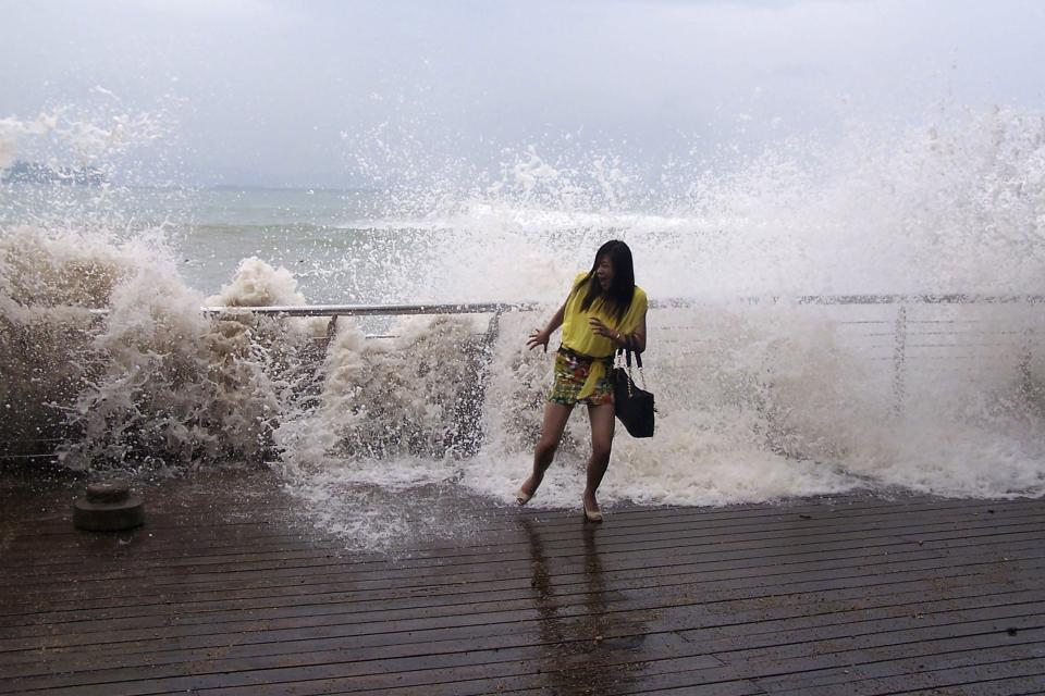 A woman reacts as a storm surge past a barrier on the shore as Typhoon Usagi approaches Shenzhen, Guangdong province, September 22, 2013. China's National Meteorological Center issued its highest alert, warning that Usagi would bring gales and downpours to southern coastal areas, according to the official Xinhua news agency. Major Chinese airlines cancelled flights to cities in the southern provinces of Guangdong and Fujian while shipping was suspended between the Chinese mainland and Taiwan, Xinhua also reported. REUTERS/Stringer (CHINA - Tags: ENVIRONMENT DISASTER) CHINA OUT. NO COMMERCIAL OR EDITORIAL SALES IN CHINA