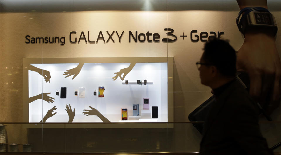 In this photo taken on Jan. 7, 2014, a man walks by a billboard for Samsung Electronics' Galaxy Note 3 at a showroom of Samsung Electronics in Seoul, South Korea. For the first time in more than two years, Samsung's quarterly net profit declined from the previous quarter, the South Korean electronics powerhouse said Friday, Jan. 24, 2014, amid deepening concerns about slowing growth in smartphone markets. (AP Photo/Lee Jin-man)