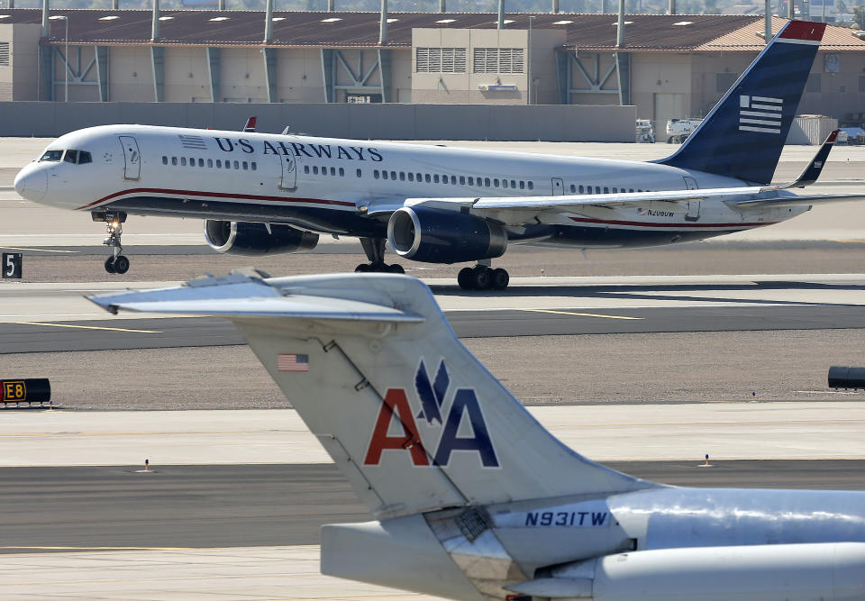 FILE - In this Thursday, Feb. 14, 2013, file photo, a U.S. Airways jet passes an American Airlines jet at Sky Harbor International Airport in Phoenix. The merger of the two airlines has given birth to a mega airline with more passengers than any other in the world. The Justice Department and a number of state attorneys general on Tuesday, Aug. 13, 2013, challenged a proposed $11 billion merger between US Airways Group Inc. and American Airlines' parent company, AMR Corp. (AP Photo/Matt York, file)