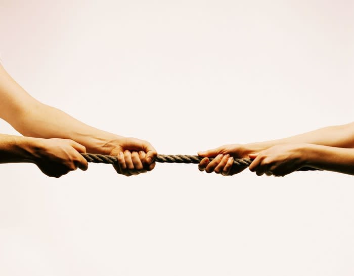 Two hands pulling on each side of a rope in a game of tug-of-war.