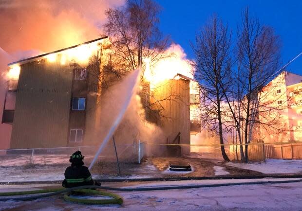 A firefighter fights the flames from the ground at Rockhill apartments in Yellowknife in 2018.