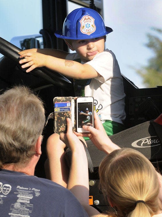 Dominic Babula, 2, gets his picture taken by his grandparents as he sits in the drivers seat of a Souderton firetruck at the National Night Out held in Franconia Park on Tuesday night.