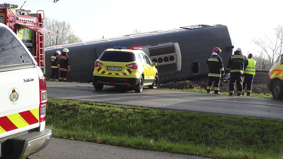 Firemen and policemen inspect the scene after a passenger train travelling on the Szentes - Hodmezovasarhely line derailed and careened into a ditch 60 metres from the site of the impact in Mindszent, Hungary, Tuesday, April 05, 2022. Five people died and over ten were injured when a van drove onto the rails and collided with a train in Mindszent, in southern Hungary. (Ferenc Donka/MTI via AP)