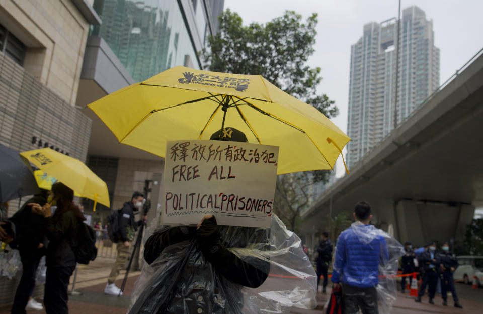 A supporter holds an umbrella and a placard outside a court in Hong Kong, Thursday, March 4, 2021. A marathon court hearing for 47 pro-democracy activists in Hong Kong charged with conspiracy to commit subversion enters its fourth day on Thursday, as the court deliberates over whether the defendants will be granted bail. (AP Photo/Vincent Yu)