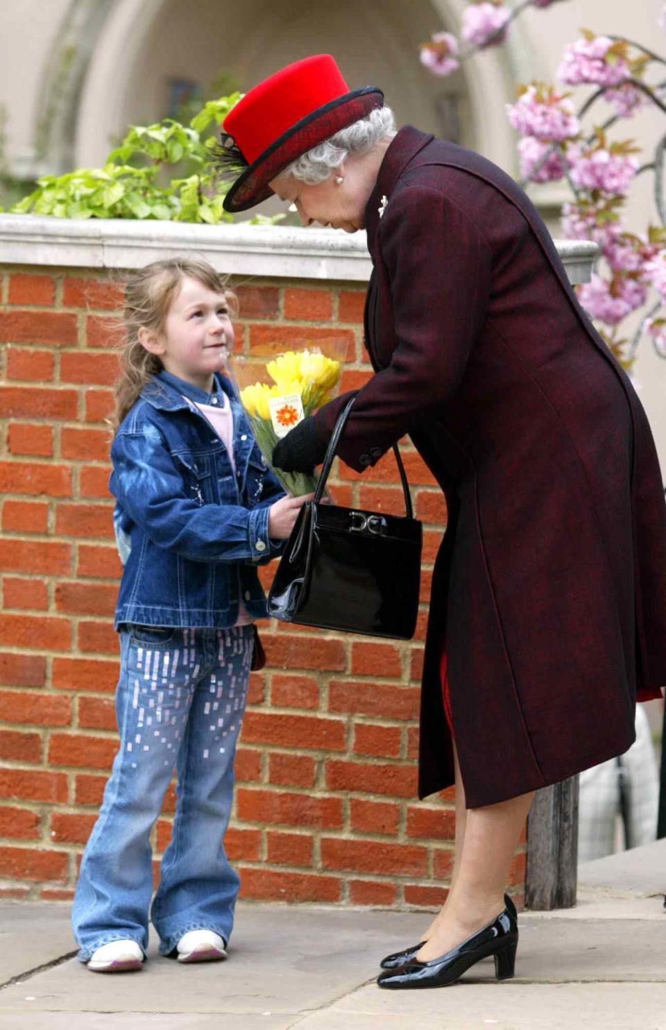 <p>The Queen traditionally receives flowers from a young child — like this adorable little girl in some sparkling jeans! — upon leaving the church.</p>