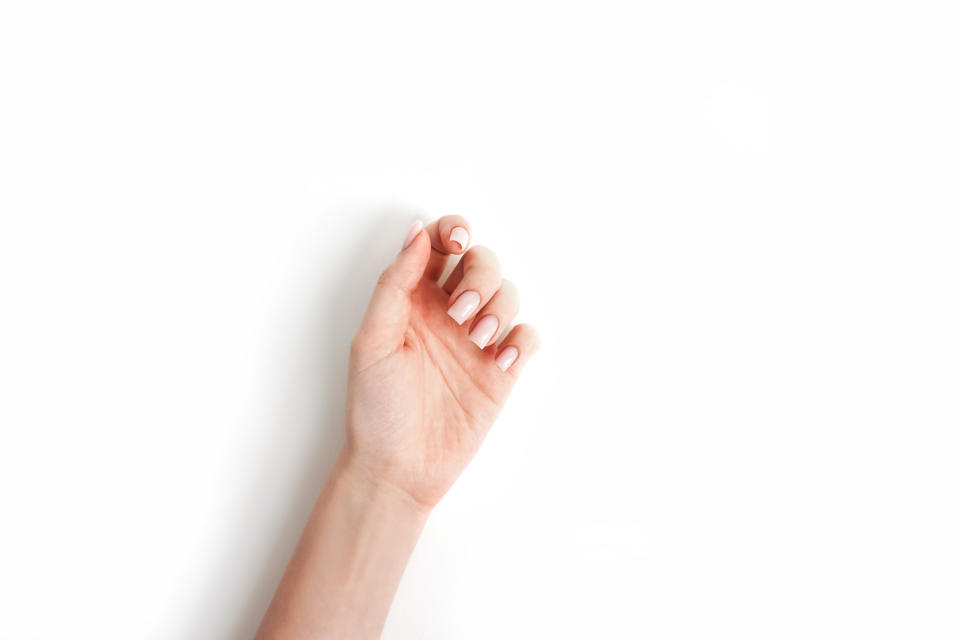 Person's hand making a 'pinkie promise' gesture on a plain background