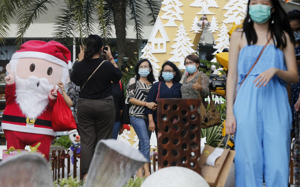 Women wearing masks to help curb the spread of the coronavirus pose for a photo with Santa in Bali, Indonesia on Tuesday, Dec. 22, 2020. Indonesia has reported more than 600,000 cases of the coronavirus. (AP Photo/Firdia Lisnawati)