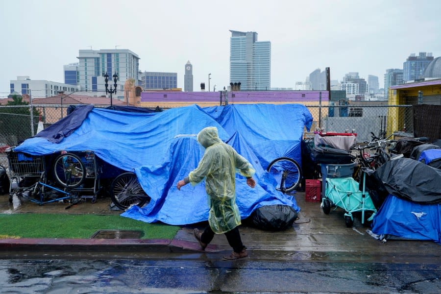 Homeless people use plastic tarps to shield themselves from a light rain brought by Tropical Storm Hilary in downtown San Diego, Sunday, Aug. 20, 2023. (AP Photo/Damian Dovarganes)