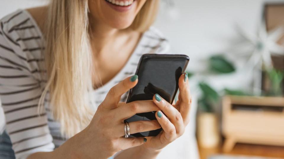 how to make friends: Young woman using cell phone on a couch at home