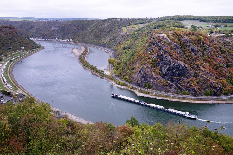 In this Wednesday, Oct.24, 2018 picture a cargo ship passes the Loreley rock at the river Rhine in St.Goar, Germany, during historically low water levels. A hot, dry summer has left German waterways at record low levels, causing chaos for the inland shipping industry, environmental damage and billions of euros of losses _ a scenario that experts warn could portend things to come as global temperatures rise. (AP Photo/Michael Probst)