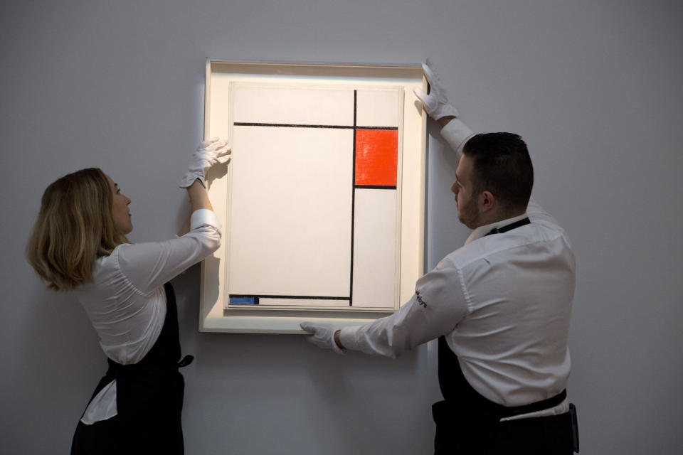 Gallery assistants hang the work Composition with Red, Blue and Grey by Piet Mondrian during a photo-call for Impressionist and Modern Art Evening Sale at Sotheby's auction house in London June 18, 2014. REUTERS/Neil Hall (BRITAIN - Tags: SOCIETY)