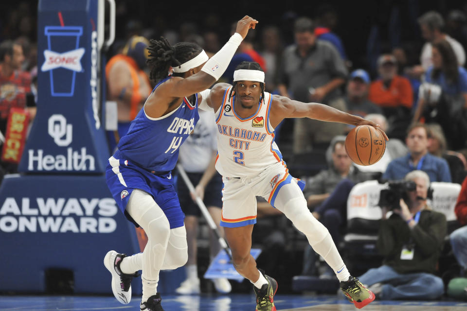 Oklahoma City Thunder guard Shai Gilgeous-Alexander (2) pushes past Los Angeles Clippers forward Terance Mann (14) in the first half of an NBA basketball game, Thursday, Oct. 27, 2022, in Oklahoma City. (AP Photo/Kyle Phillips)