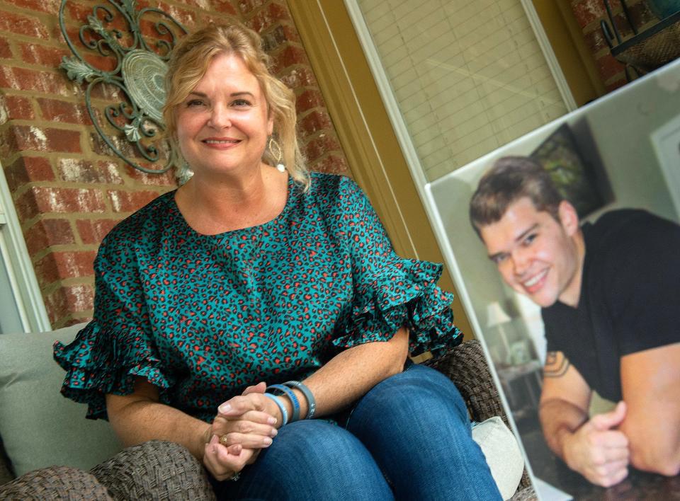 Susan Cleland, author of “Mission Vigilant: A Mother’s Crusade to Stem the Tide of Veteran Suicide”, sits outside her Madison, Miss., home Thursday, Sept. 14, 2023. In the foreground is a photo fo her son, veteran Michael Vinson, who she lost to suicide in 2019.