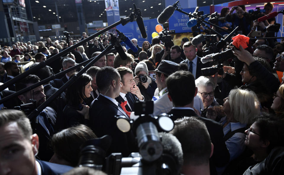 French President Emmanuel Macron is surrounded by the members of the media as he discusses with a farmer during the opening of the 56th International Agriculture Fair (Salon de l'Agriculture) at the Porte de Versailles exhibition center in Paris, France, Saturday, Feb. 23, 2019. Macron pledged to protect European farming standards and culinary traditions threatened by aggressive foreign trade practices that see food as a "product like any other." (Julien de Rosa/Pool Photo via AP)