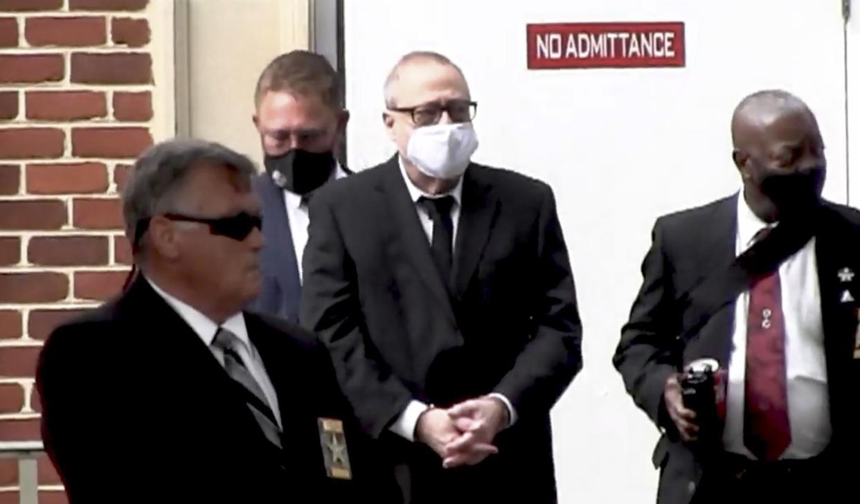 In this image from video, Gregory McMichael, second from right, is led by security officers from the Glynn County Courthouse in Brunswick, Ga.,  on Wednesday.