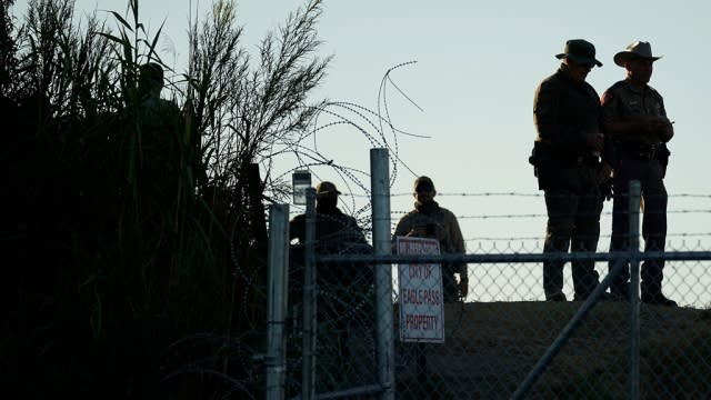 Texas troopers stand near concertina wire along the banks of the Rio Grande in Texas