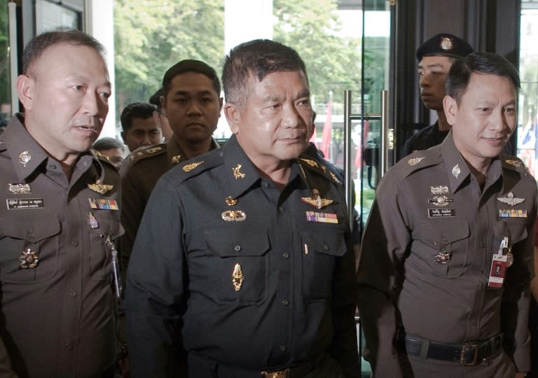 Thai Army Lieutenant General Manas Kongpan (C) surrounded by police officers when he turned himself in at the police headquarters in Bangkok