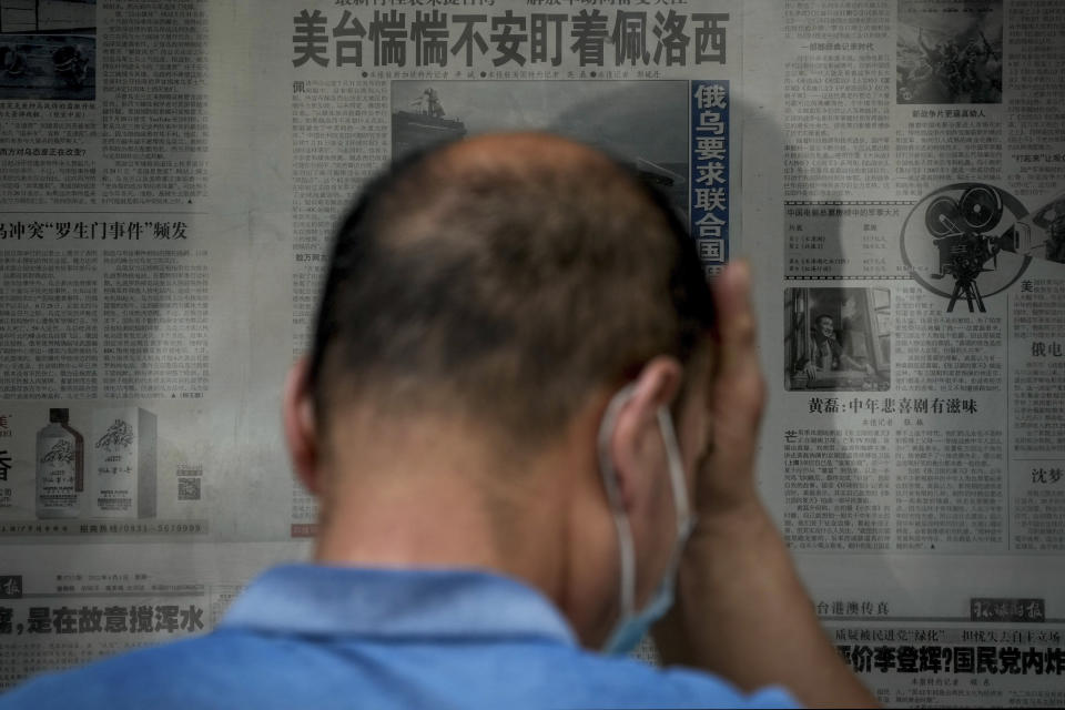 A man rubs his forehead as he reads a newspaper headline reporting "U.S. Taiwan staring anxiously on U.S. House Speaker Nancy Pelosi" at a stand in Beijing, Tuesday, Aug. 2, 2022. Pelosi arrived in Malaysia on Tuesday for the second leg of an Asian tour that has been overshadowed by an expected stop in Taiwan, which would escalate tensions with Beijing that claims the self-ruled island as its own territory. (AP Photo/Andy Wong)