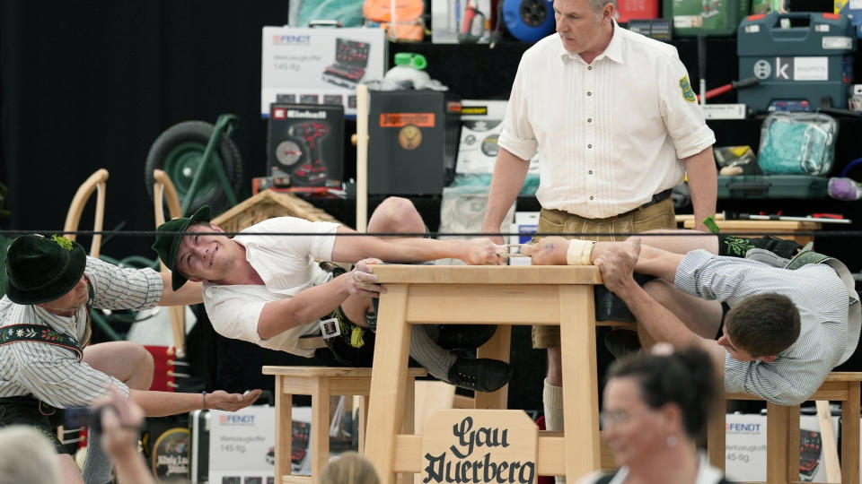 A man dressed in traditional clothes tries to pull his opponent over the table at the German Championships in Fingerhakeln or finger wrestling, in Bernbeuren, Germany, Sunday, May 12, 2024. Competitors battled for the title in this traditional rural sport where the winner has to pull his opponent over a marked line on the table. (AP Photo/Matthias Schrader)
