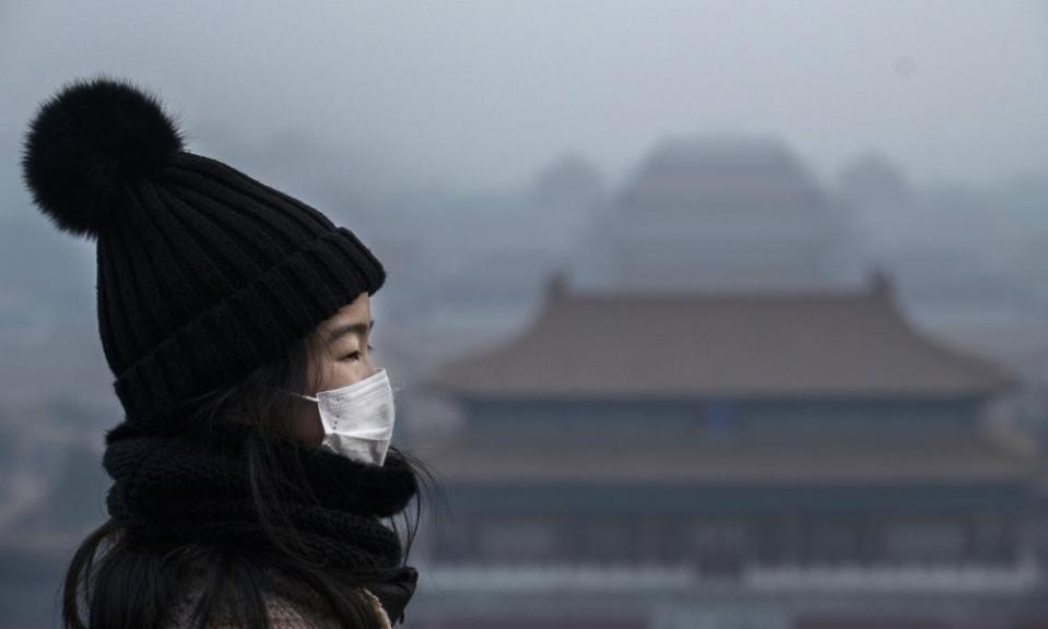 A girl wears a protective mask as she looks towards the Forbidden City in Beijing, which was closed by authorities during the Chinese New Year holiday on 26 January.